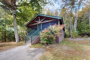 Una cabaña con porche, escaleras y vistas del bosque circundante.