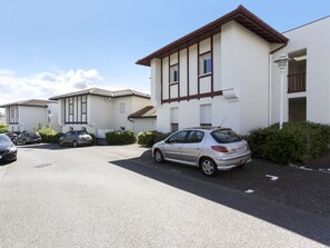 A residential building with a parking area, multiple cars, and a clear sky. - Appartement Casau - Welkeys (Anglet)
