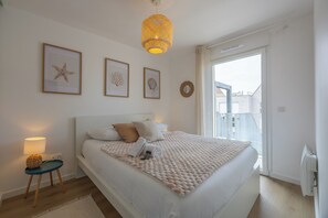 Ein Schlafzimmer mit Bett, Nachttisch, Lampe und einem gerahmten Kunstwerk an der Wand.