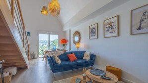 Ein modernes Wohnzimmer mit einem blauen Sofa, einem Holztisch und einer Treppe.
