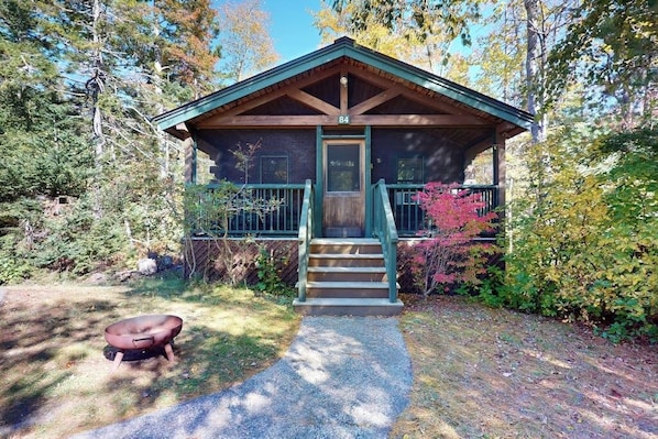 Eine Hütte mit Veranda, einer Holztür und der Zahl 84 darüber.
