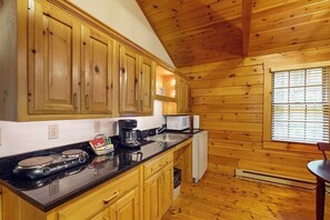 Una cocina con armarios de madera, estufa, microondas y ventana con persianas.