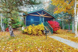 A cabin with a porch, a staircase, and a mailbox.