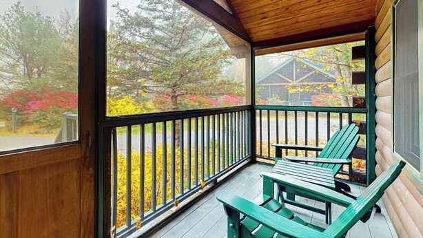 Un portico in legno con una panchina e un tavolo, vista su alberi e un edificio sullo sfondo.
