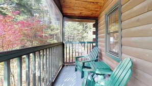 Eine hölzerne Veranda mit Blick auf Bäume und eine Holzhütte.