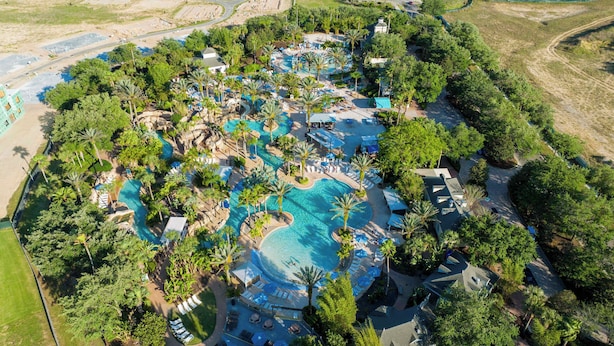 An aerial view of a resort with multiple swimming pools, palm trees, and lounge areas. - Brand New | 6BR Reunion Pool & Spa Villa 7894 (Kissimmee)