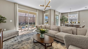 A modern living room with a sectional sofa, a coffee table, and a dining area with a chandelier. - Brand New | 6BR Reunion Pool & Spa Villa 7894 (Kissimmee)