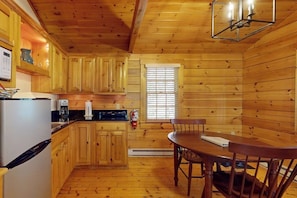 A wooden cabin interior with a kitchen, dining table, and chairs. - Comfortable dog-friendly cabin with fireplace & kitchenette near hiking trails (Northport)