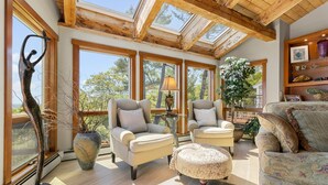 A spacious living area with large windows, a wooden ceiling, and a comfortable seating arrangement. - Elegant ocean view home with breathtaking views, private hot tub & large deck (Rockport)