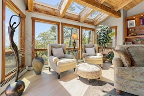 A spacious living area with large windows, a wooden ceiling, and a comfortable seating arrangement.