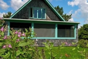 A house with a gabled roof, a porch with green trim, and a garage.