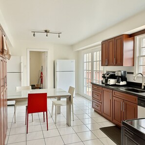 A modern kitchen with a dining area, featuring a refrigerator, stove, and coffee maker. - Private Room in North York | Shared Bath (Toronto)