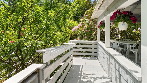 A covered outdoor area with a white railing, a table, and chairs. - Ledgewood 7 - Large home in Seal Harbor. Walk, hike, bike on trails right out your front door (Mount Desert)
