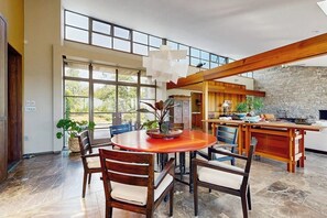 A spacious dining area with a round table, wooden chairs, and a large window providing a view of the outdoors. - Stylish Coastal Retreat w/ Spacious Layout & Access to the St. George Peninsula (St. George)