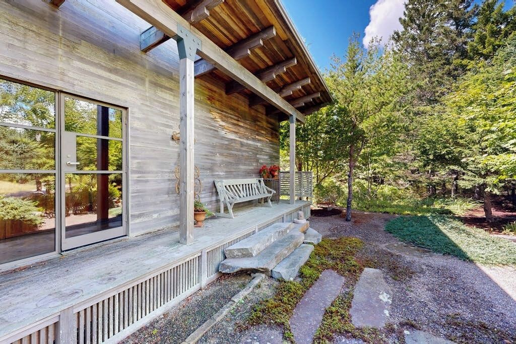 Eine Holzhütte mit Veranda, großen Fenstern und einem Steinweg, der zum Eingang führt.
