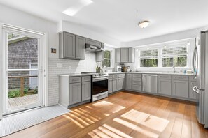 Una cocina moderna con armarios grises, un refrigerador de acero inoxidable y un ventanal amplio.