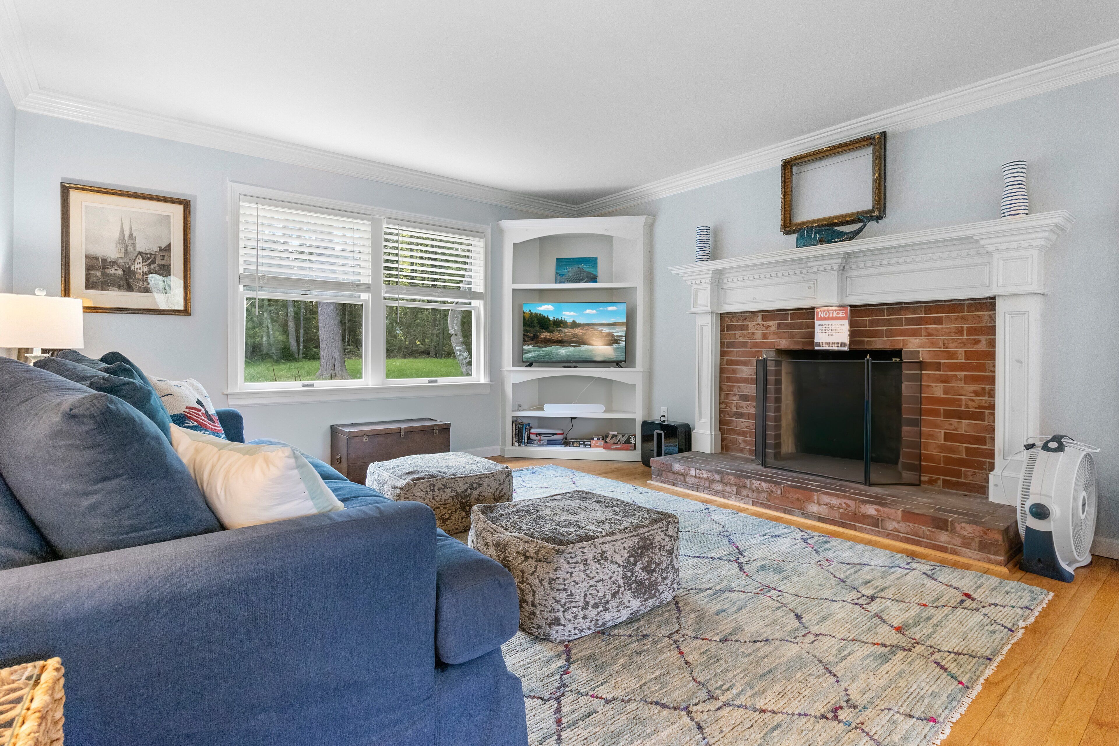A living room with a blue sofa, ottomans, a fireplace, and a television.