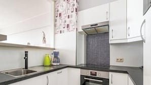 Una cocina con armarios blancos, un microondas y una cafetera sobre la encimera.