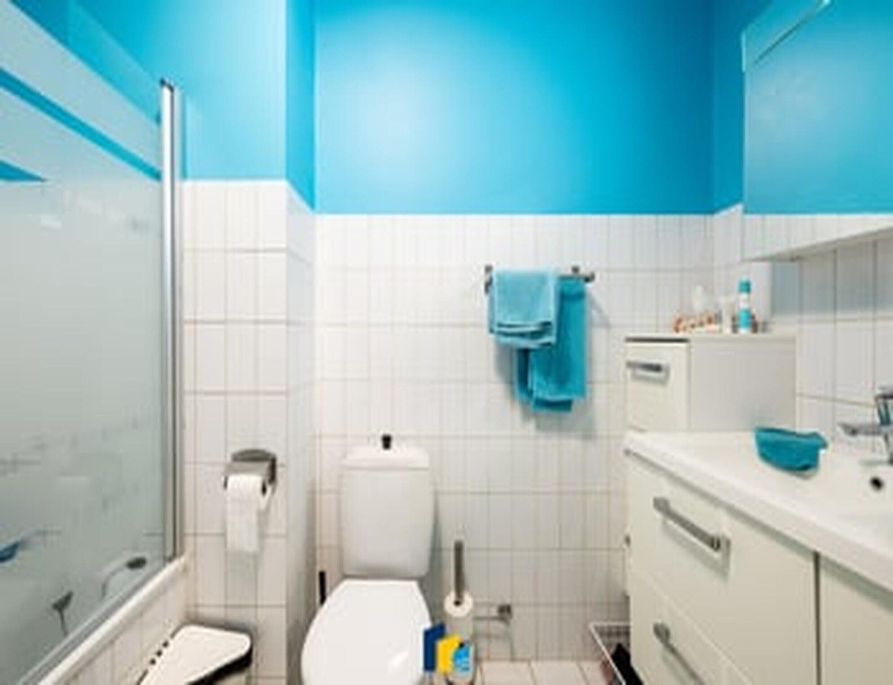 A bathroom with a glass shower enclosure, a toilet, a sink with a mirror, and a towel rack.
