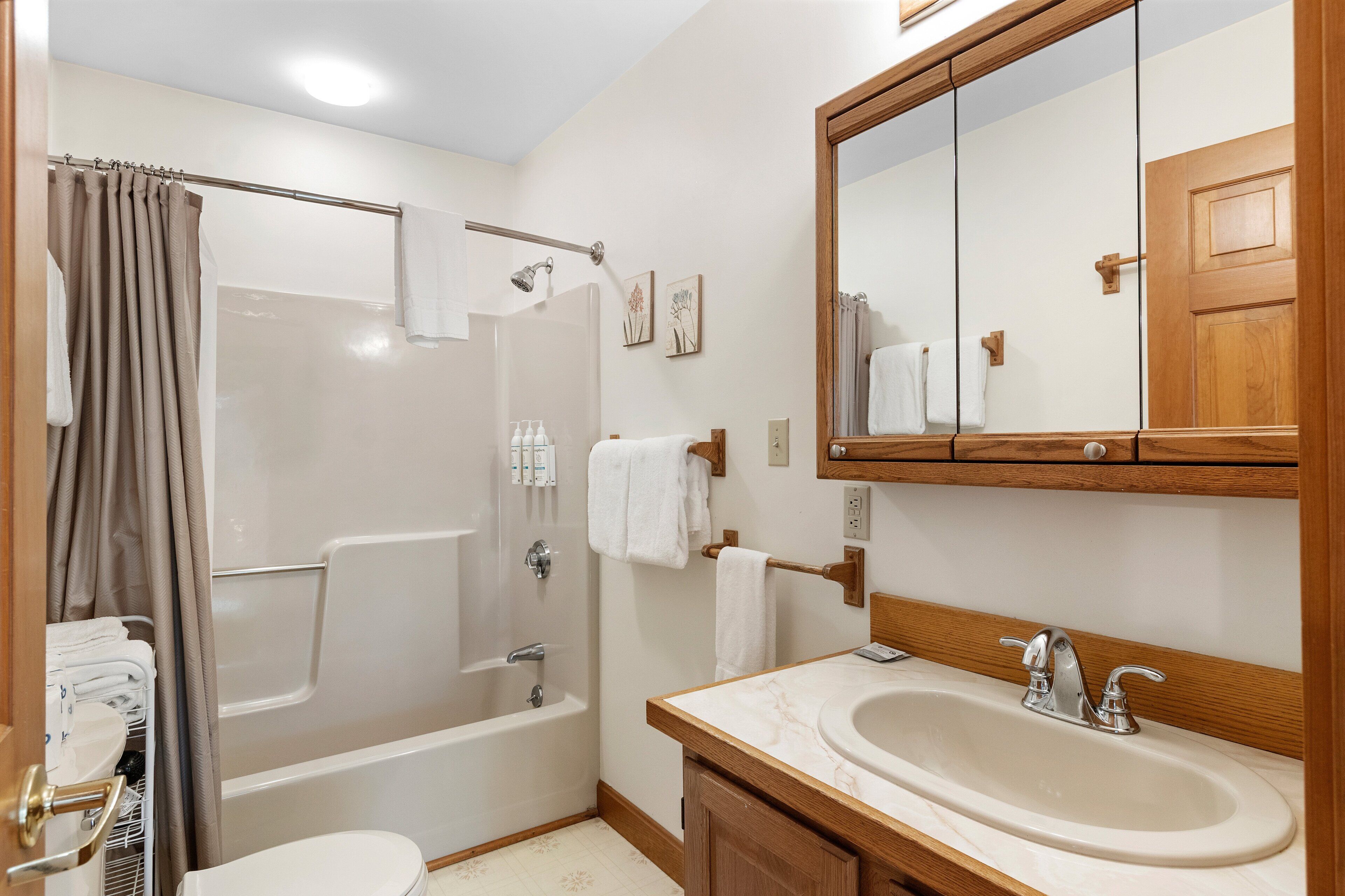 A bathroom with a bathtub, toilet, sink, and a large mirror.