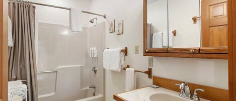 A bathroom with a bathtub, toilet, sink, and a large mirror.