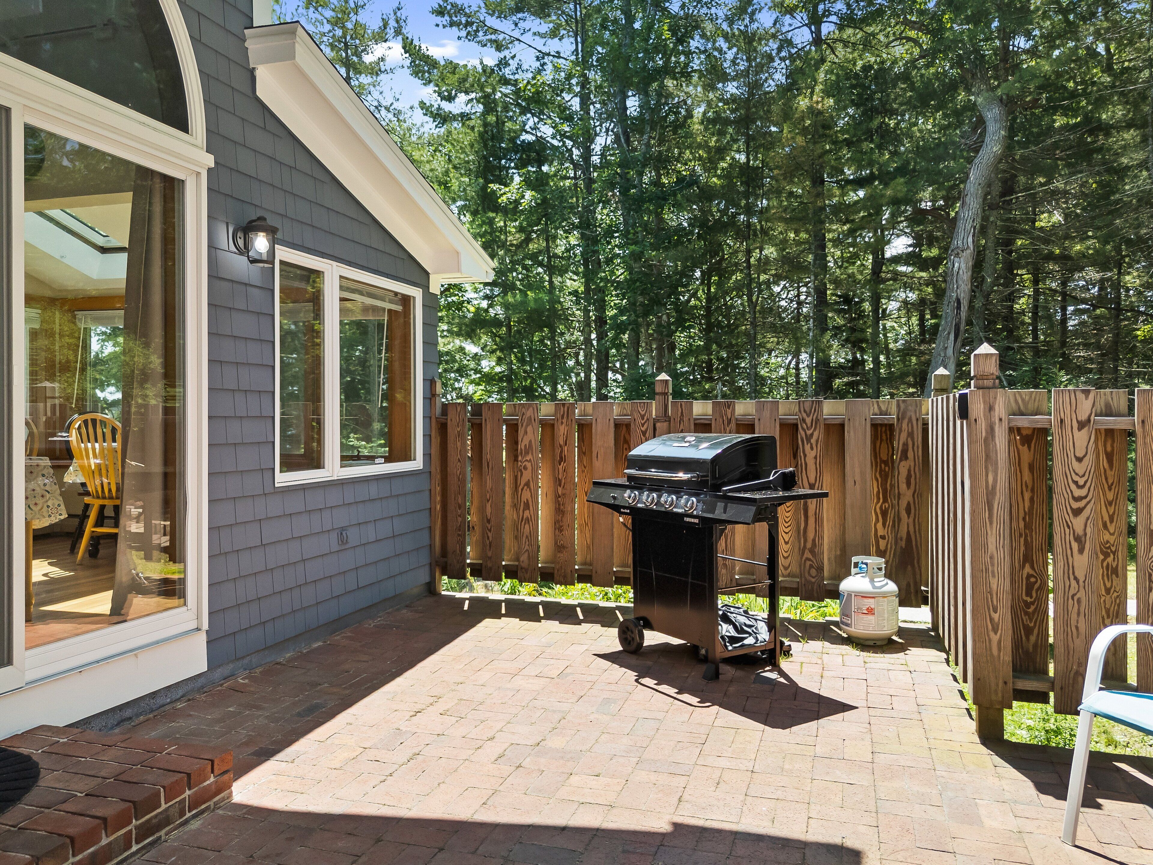 Un jardin avec un barbecue, une clôture en bois et un espace patio.