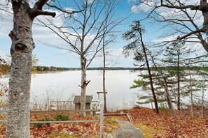 A lakeside view with a dock, trees, and a small cabin. - High View- Serene waterfront home w/ a dock, large deck & amazing views! (Harpswell)