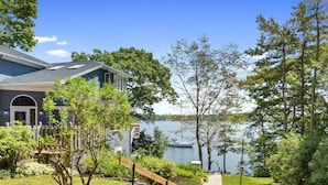 A house with a view of a lake, a wooden deck, and a pathway leading to the water. - High View- Serene waterfront home w/ a dock, large deck & amazing views! (Harpswell)