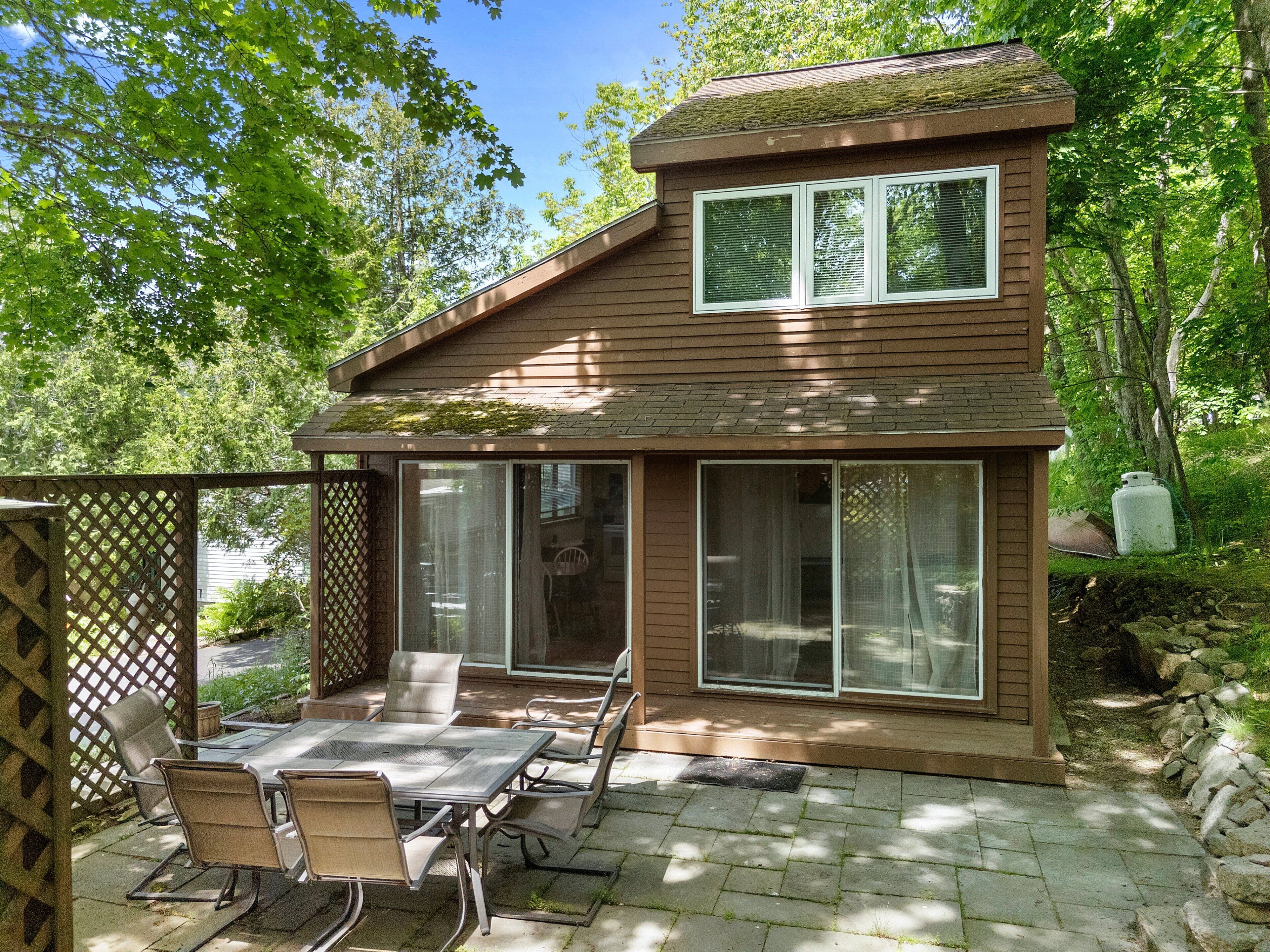 A house with a patio, a dining table with chairs, and a covered outdoor area.
