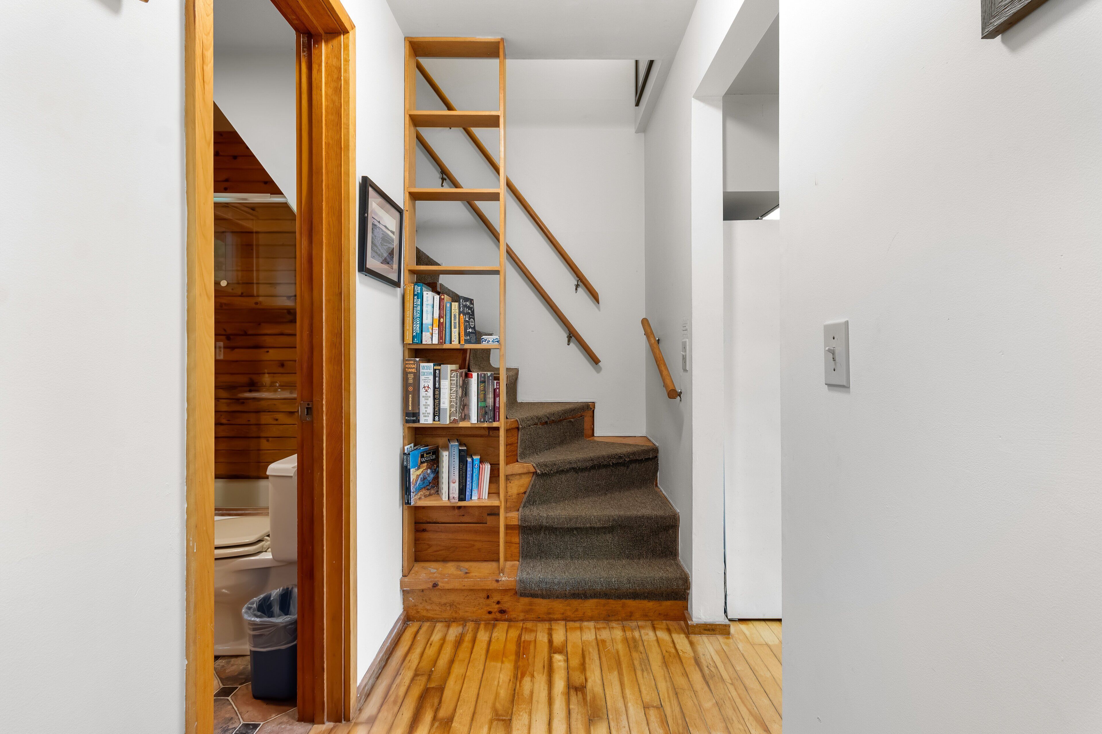 Eine Treppe mit hölzernem Geländer, Teppichstufen und einem Bücherregal mit Büchern.