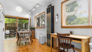 A compact kitchen with a dining area, wooden flooring, and large windows. - Ledgewood 9 - Charming Cottage near Seal Harbor Beach and hiking trails (Mount Desert)
