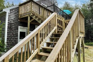 A wooden staircase leading to a deck with a black railing and a blue umbrella. - Charming apartment with ocean views, private deck, and easy bay access (Trenton)