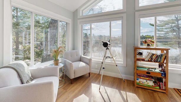 A room with large windows, a tripod, and a bookshelf.