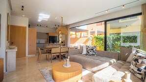 Ein modernes Wohnzimmer mit einer Couch, einem Esstisch und einer Küche im Hintergrund.