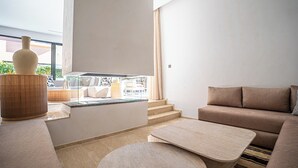 Ein modernes Wohnzimmer mit Sofa, Couchtisch, Lampe und Blick ins Freie.