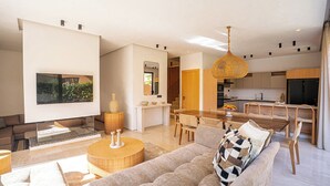 Ein modernes Wohnzimmer mit Sofa, Couchtisch, Fernseher und einem Essbereich mit Tisch und Stühlen.