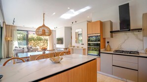 Eine moderne Küche mit Marmorarbeitsplatte, Holzschränken und einem eingebauten Backofen.