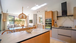 Eine moderne Küche mit Marmorarbeitsplatte, Holzschränken und einem eingebauten Backofen.