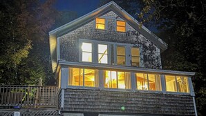 A two-story building with large windows, a gabled roof, and a wooden exterior. - Idyllic Lakefront Retreat:  pvt dock & beach for kayaking, swimming & fishing (Swanville)