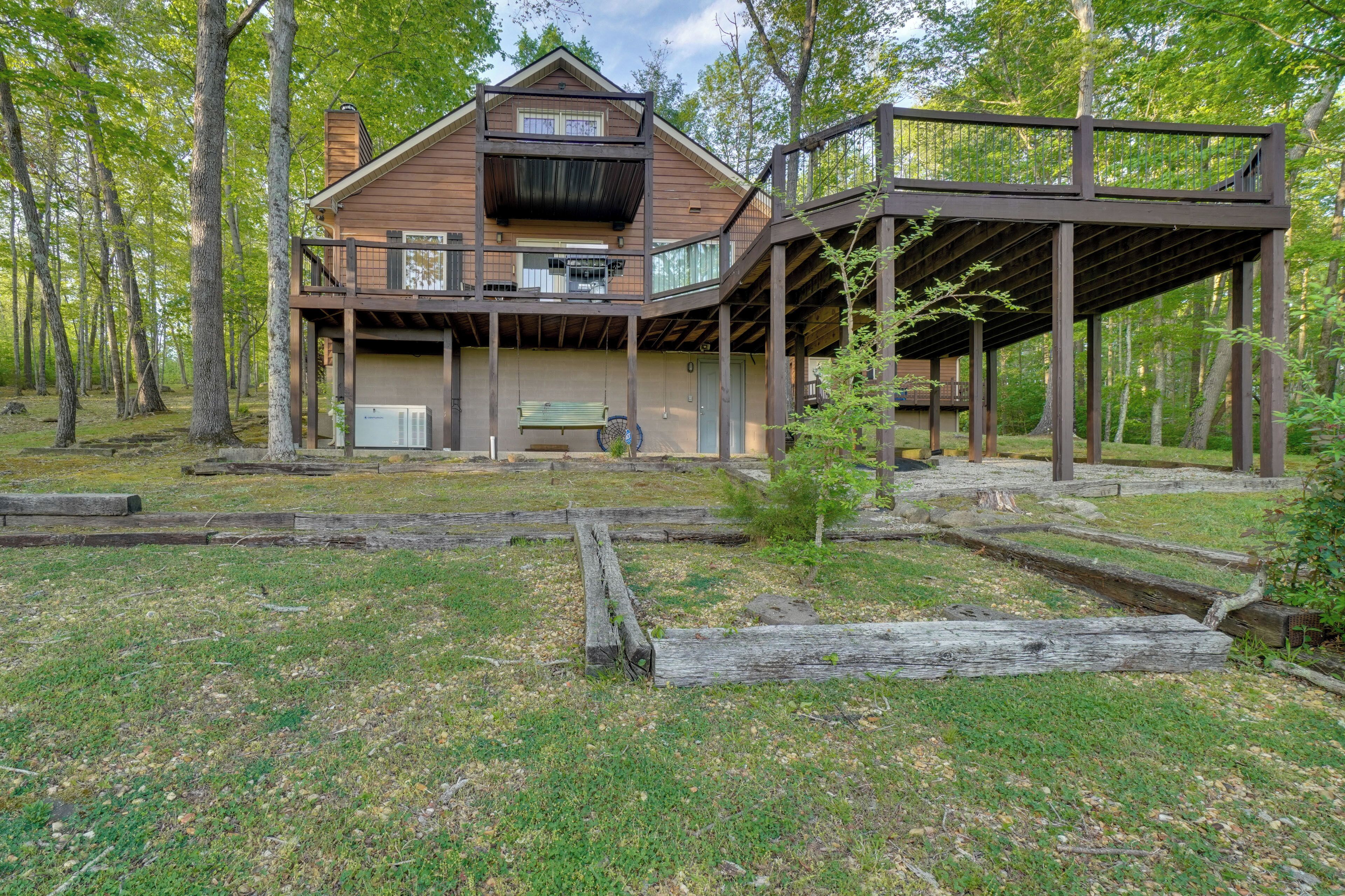 A cabin with a deck, surrounded by trees.