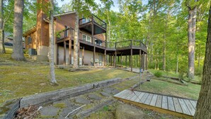 A modern house with a wooden deck, surrounded by trees.