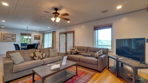 A living room with a sofa, coffee table, TV, and ceiling fan.