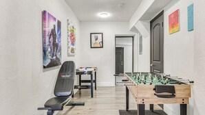 Una habitación con mesa de futbolín, escritorio con silla y cinta de correr.