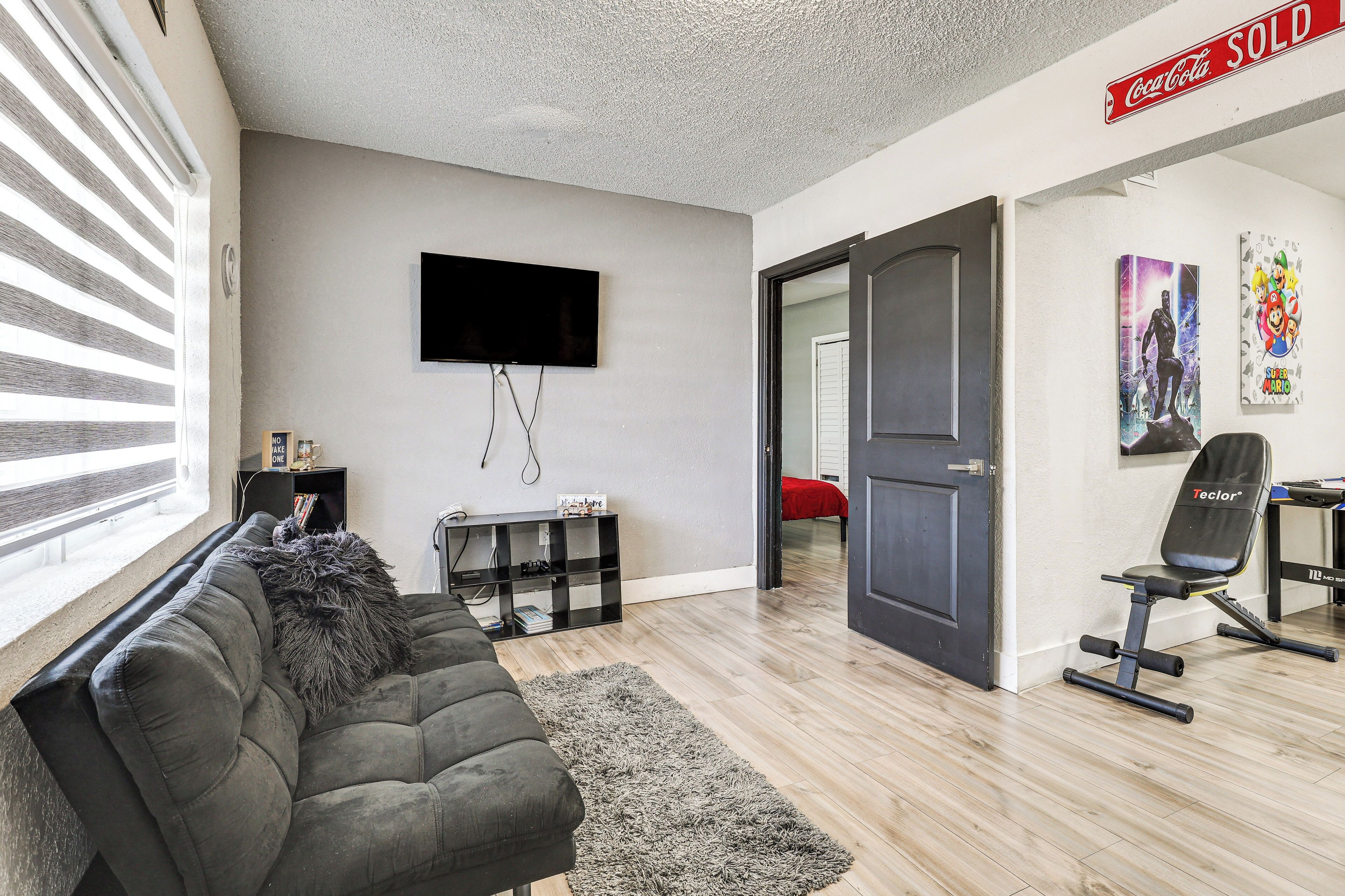 A living room with a sofa, a TV, a bookshelf, and a door leading to another room.