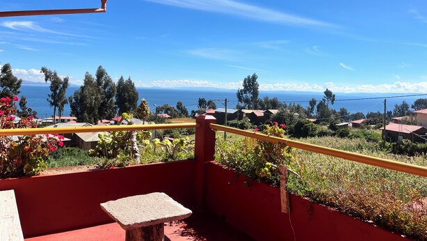 Ein Balkon mit Blick auf das Meer, umgeben von Grünflächen und Gebäuden.