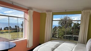 Ein Hotelzimmer mit einem Bett, einem runden Tisch und großen Fenstern mit Blick ins Freie.