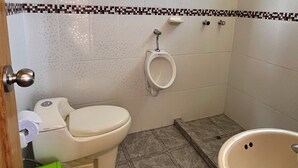 Ein Badezimmer mit Toilette, Urinal und Badewanne.