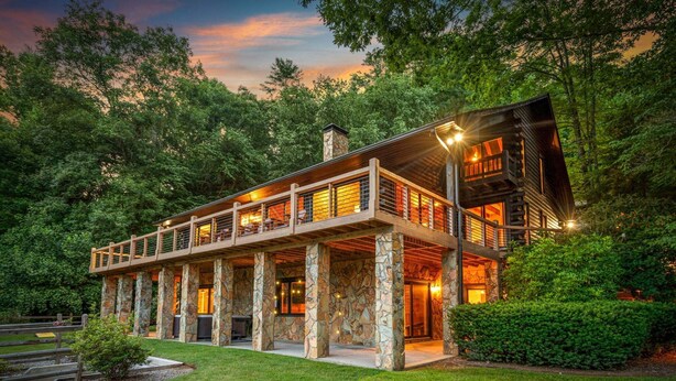 A modern log cabin with a stone foundation, large windows, and a covered outdoor area. - Swimming Bear Lodge - Lakefront | Platform Dock | Pet Friendly | Game Room (Cherry Log)