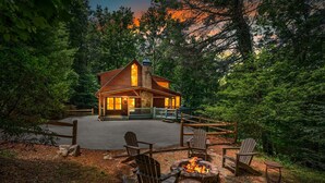 Un chalet doté d’un foyer, de fauteuils Adirondack et d’une cheminée en pierre.