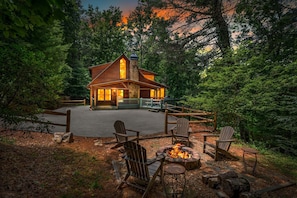 Eine Lodge mit Feuerstelle, Adirondack-Stühlen und einem Steinkamin.